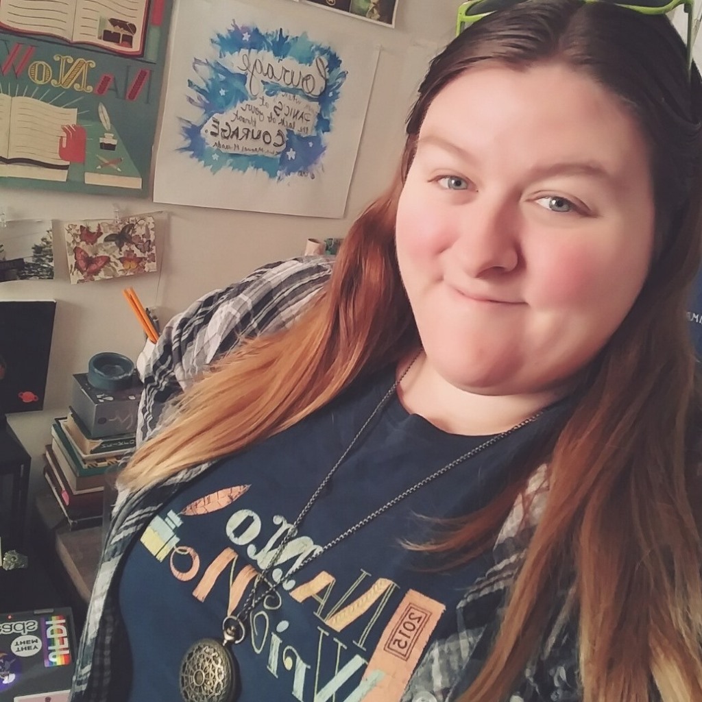 Elayna smiling in a colorful room while wearing a NaNoWriMo t-shirt
